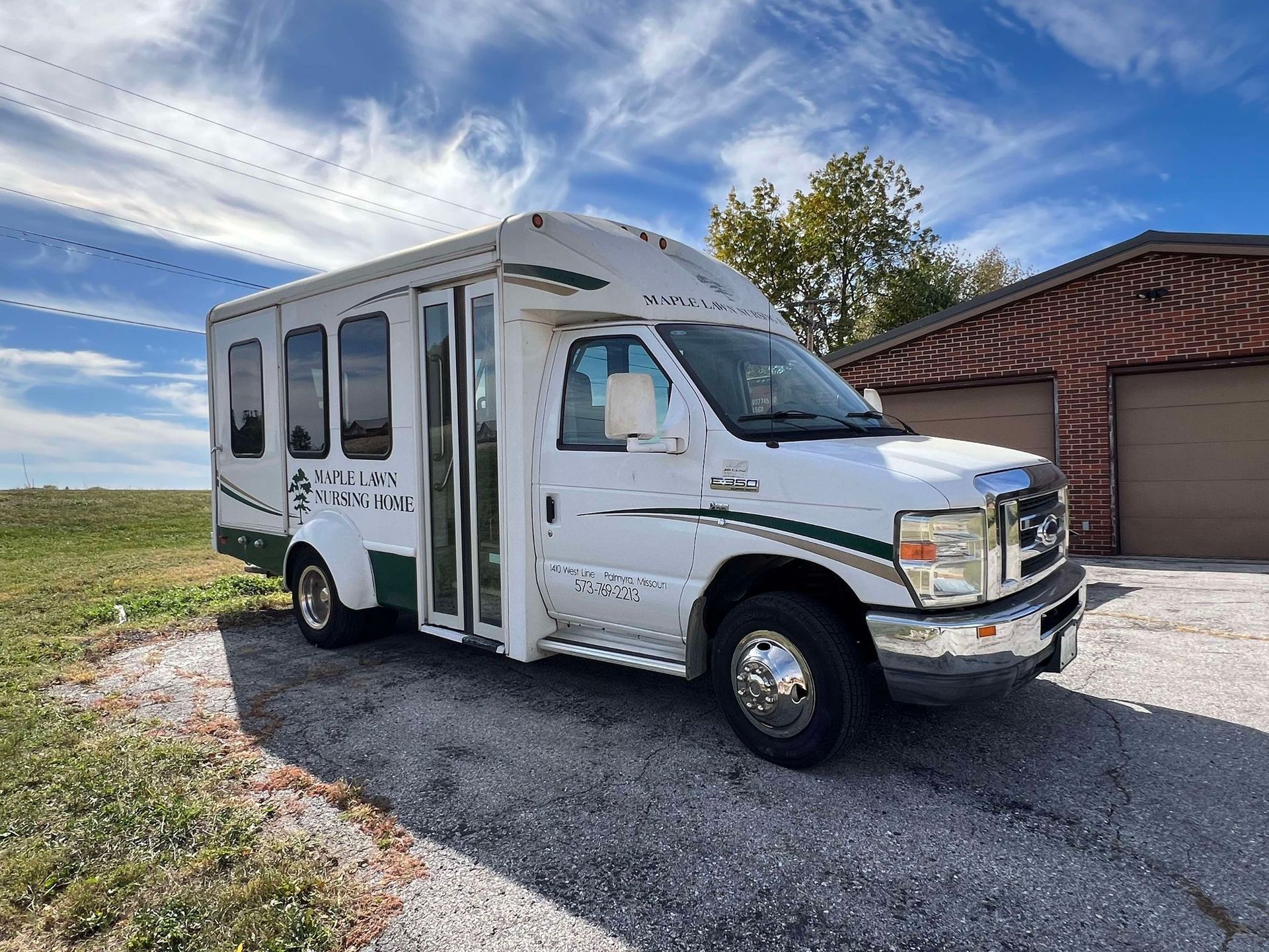 A white bus is parked in front of a garage.