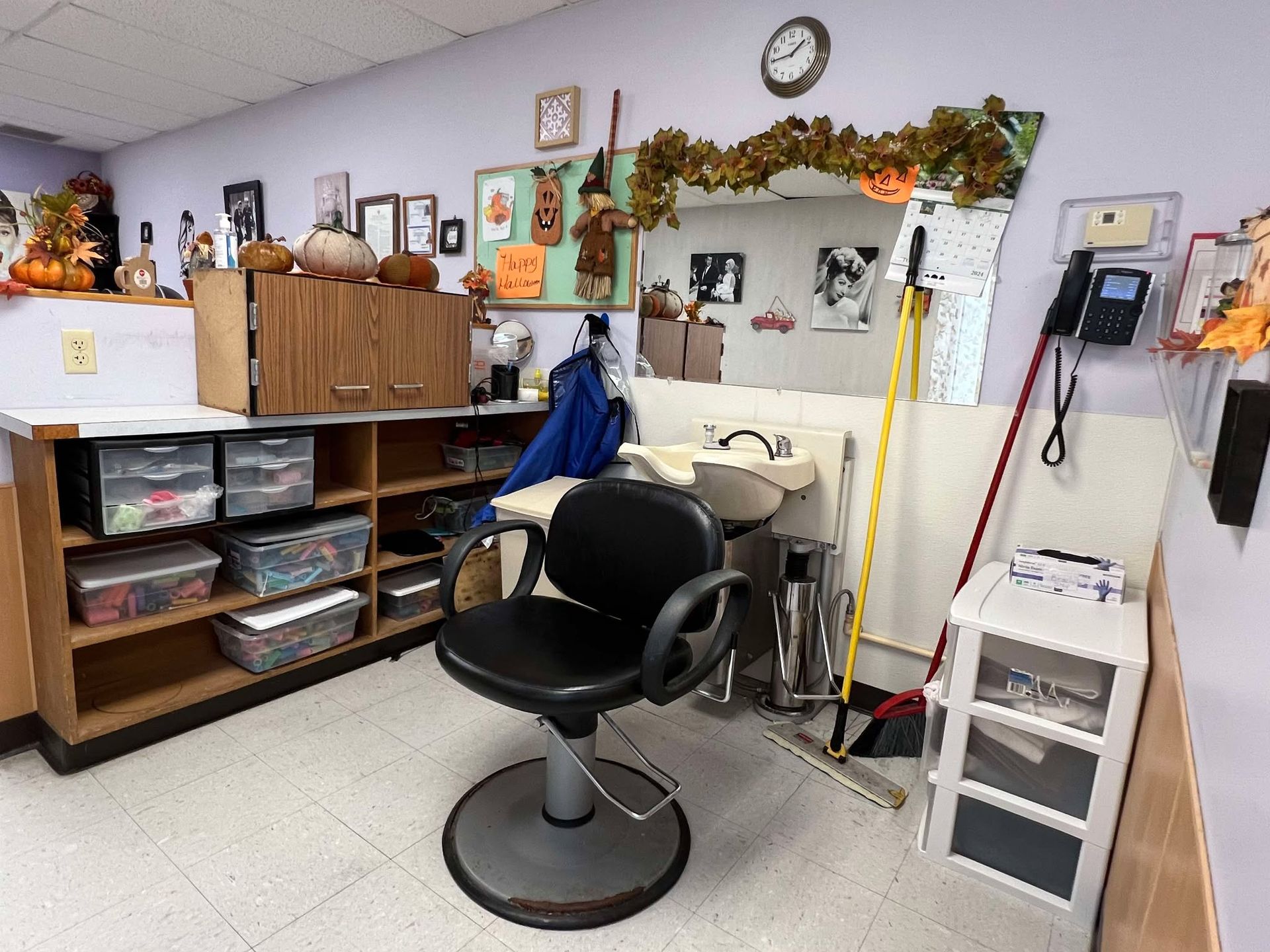 A hair salon with a black chair and a sink