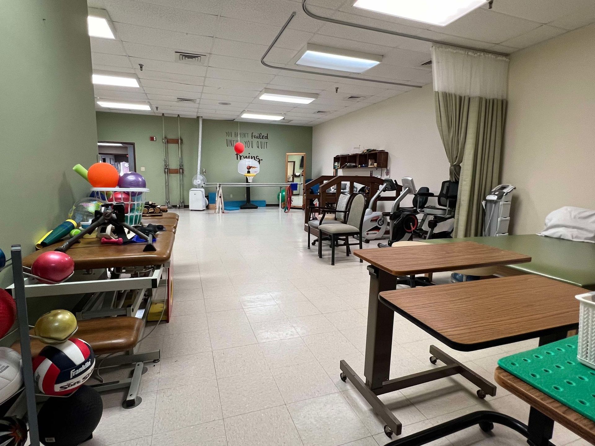 A large room with tables , chairs , exercise equipment and balloons.