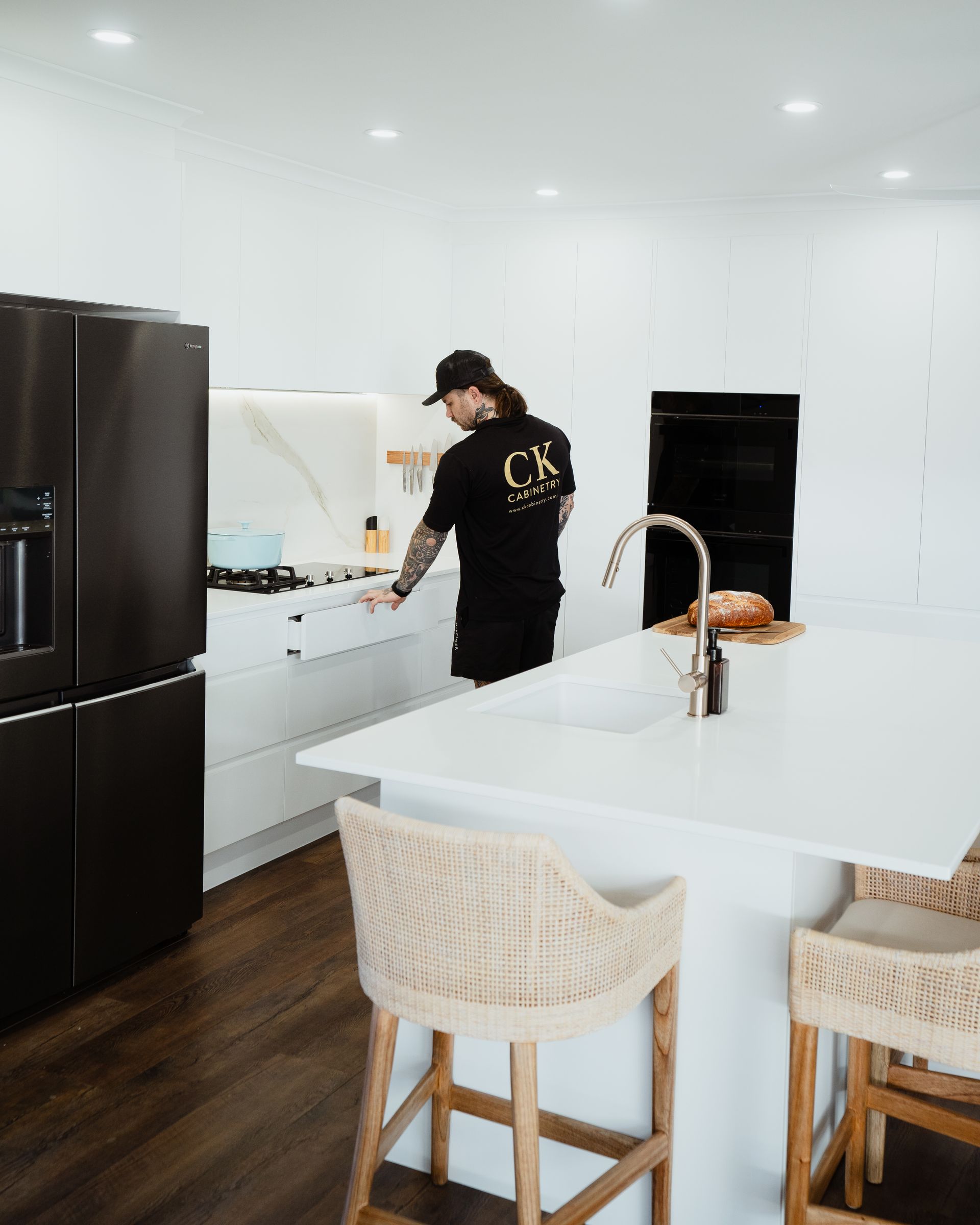 A Man is Sitting on the Floor in a Kitchen Holding a Towel — CK Cabinetry in Coolum Beach, QLD