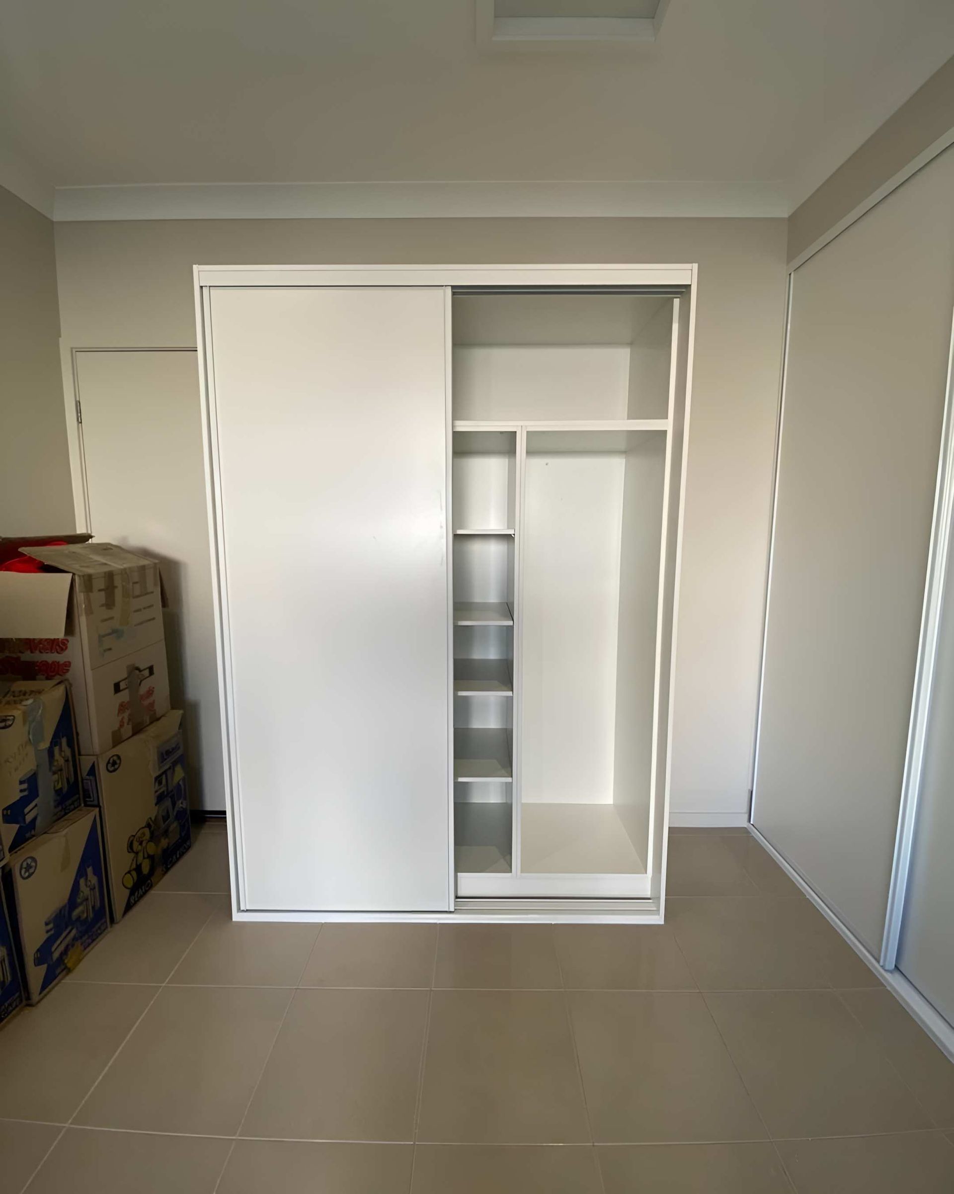 A White Wardrobe With Sliding Doors in a Room — CK Cabinetry in Maroochydore, QLD