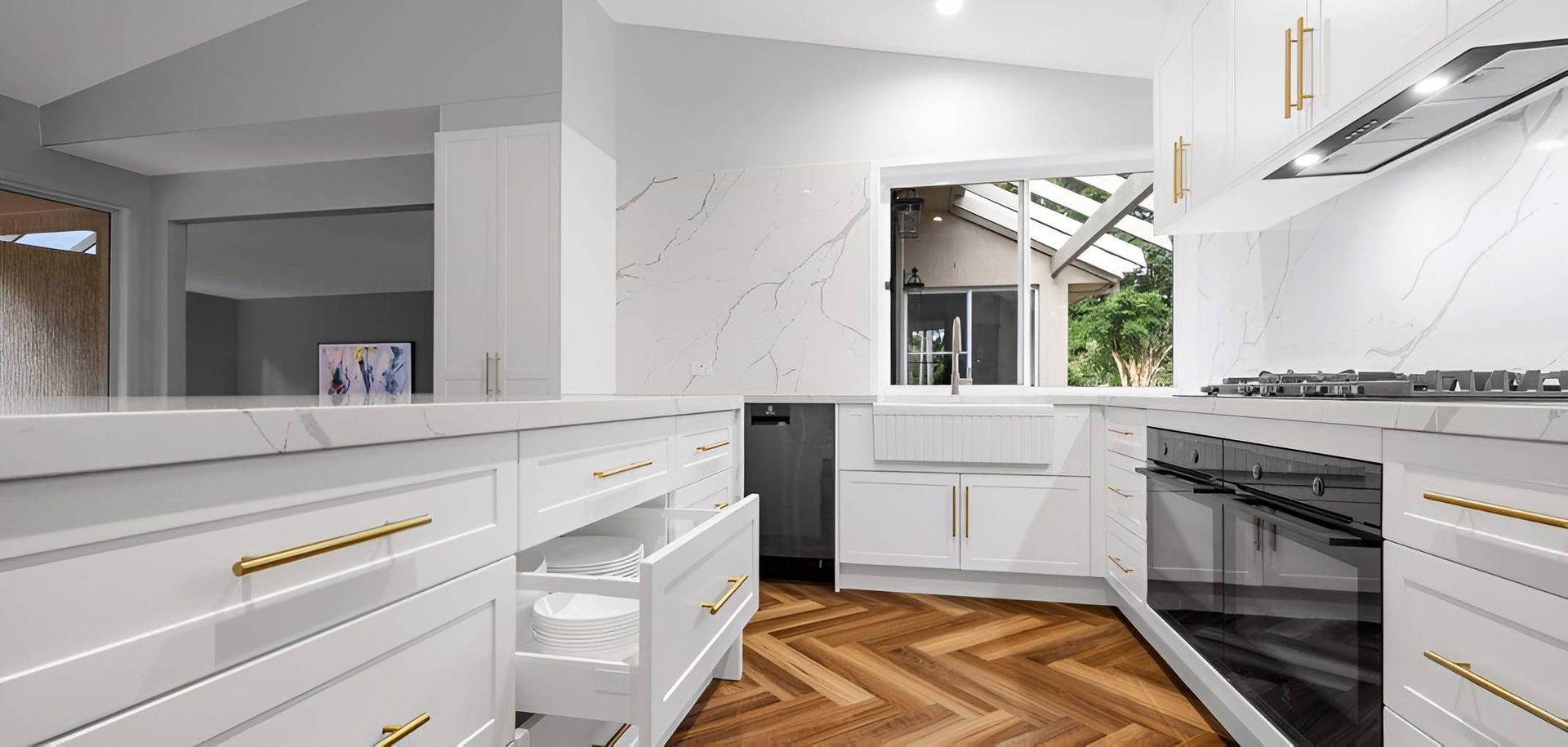 A Kitchen With White Cabinets and Gold Handles and a Wooden Floor — CK Cabinetry in Coolum Beach, QLD