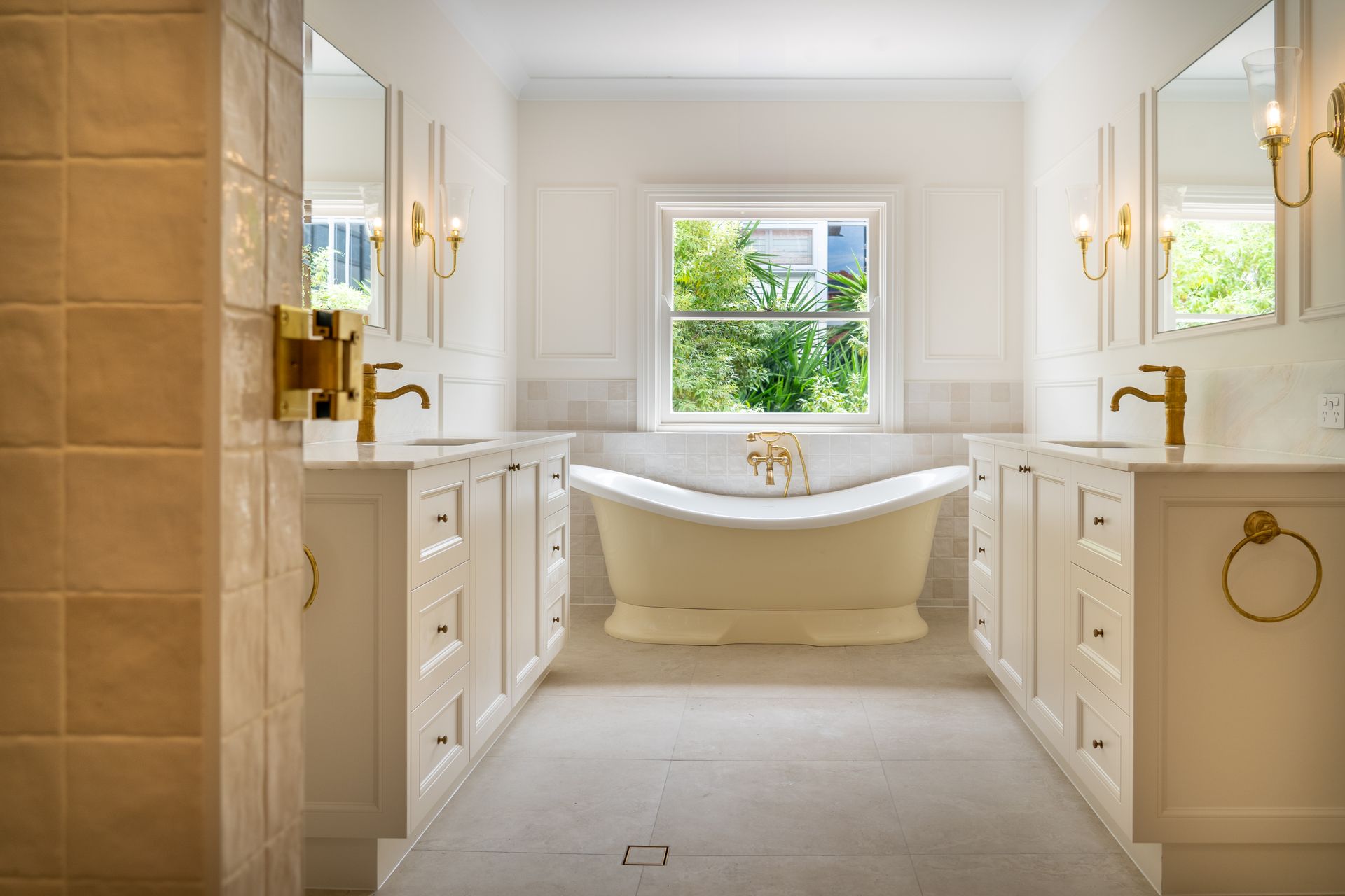 Elegant white bathroom with a clawfoot tub centered under a window, flanked by matching vanities — CK Cabinetry in Coolum Beach, QLD
