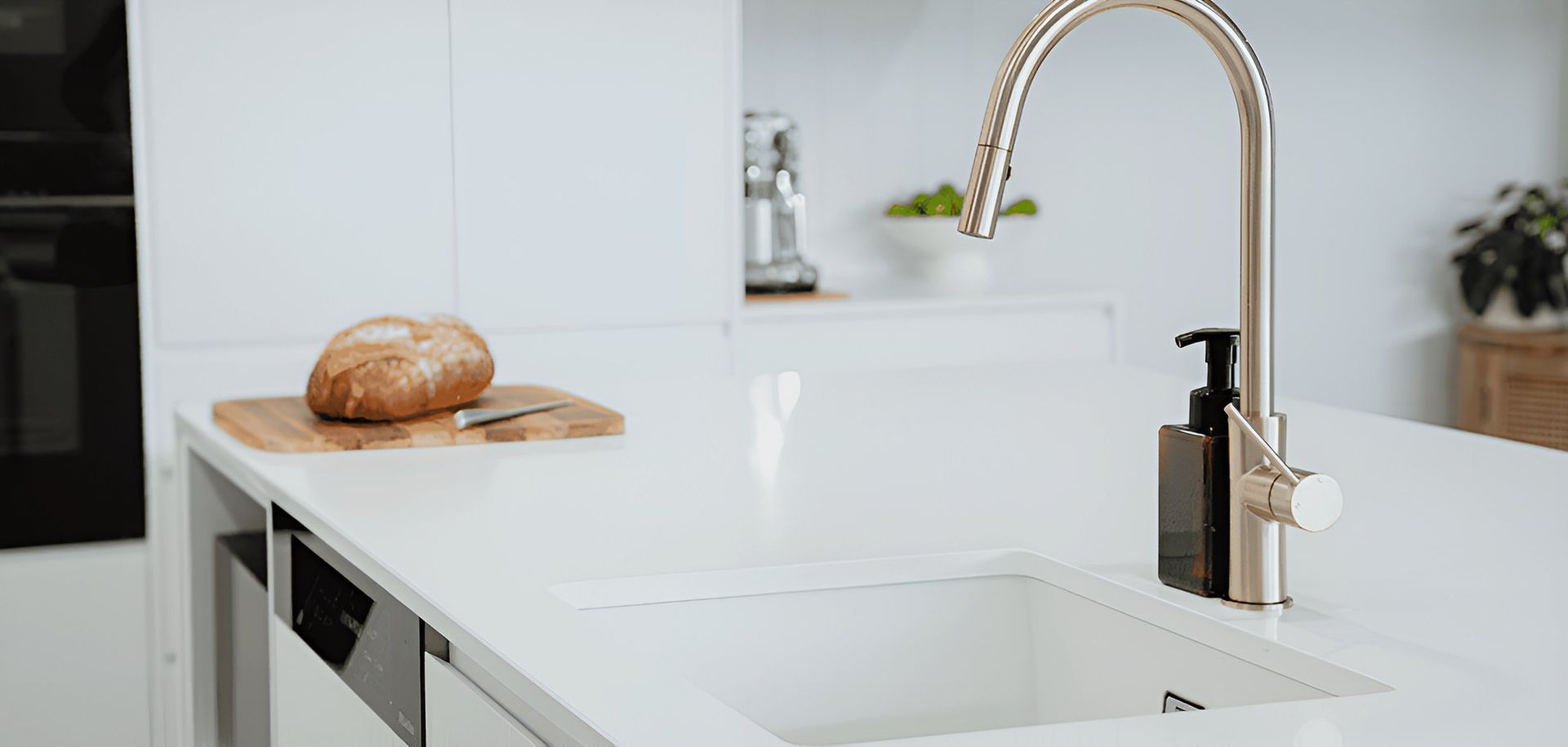 A Kitchen Sink With a Faucet and a Loaf of Bread on a Cutting Board — CK Cabinetry in Coolum Beach, QLD