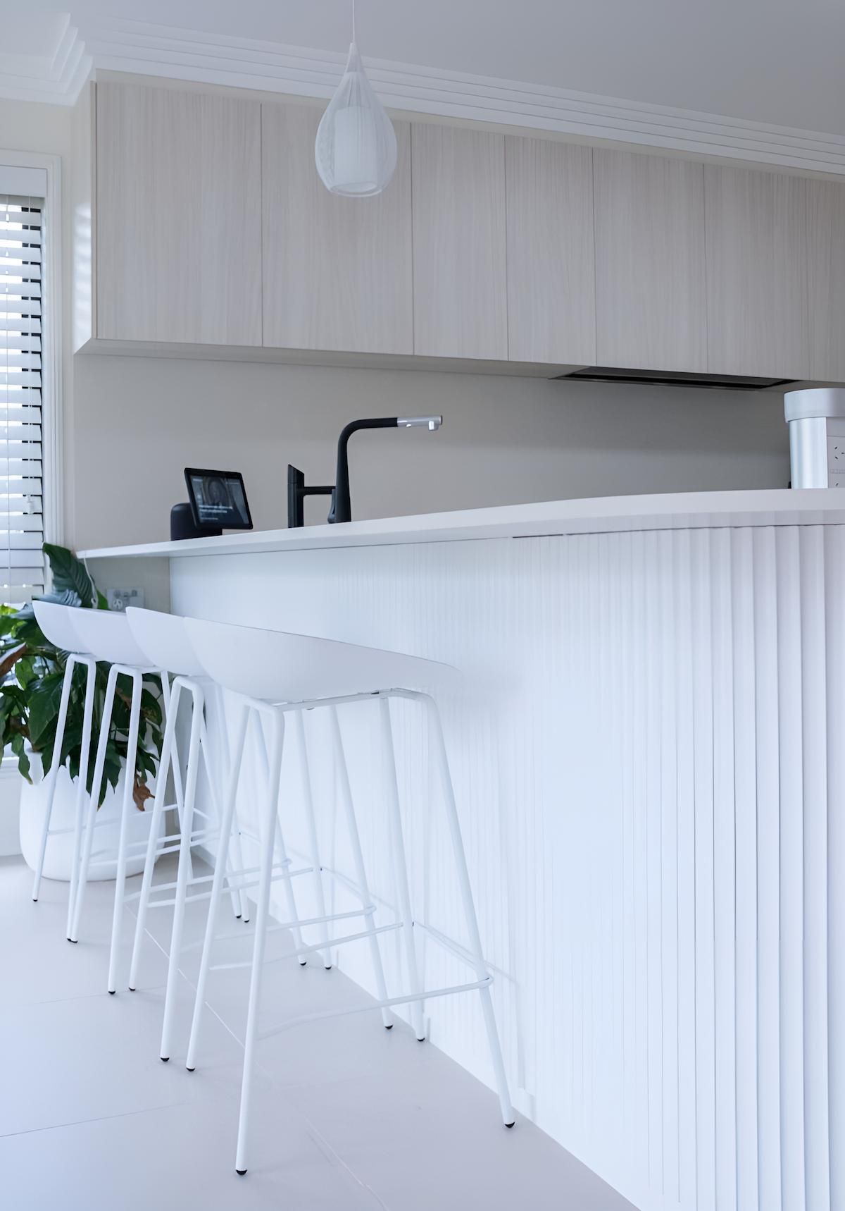 A Kitchen With White Cabinets and Stools and a Sink — CK Cabinetry in Coolum Beach, QLD