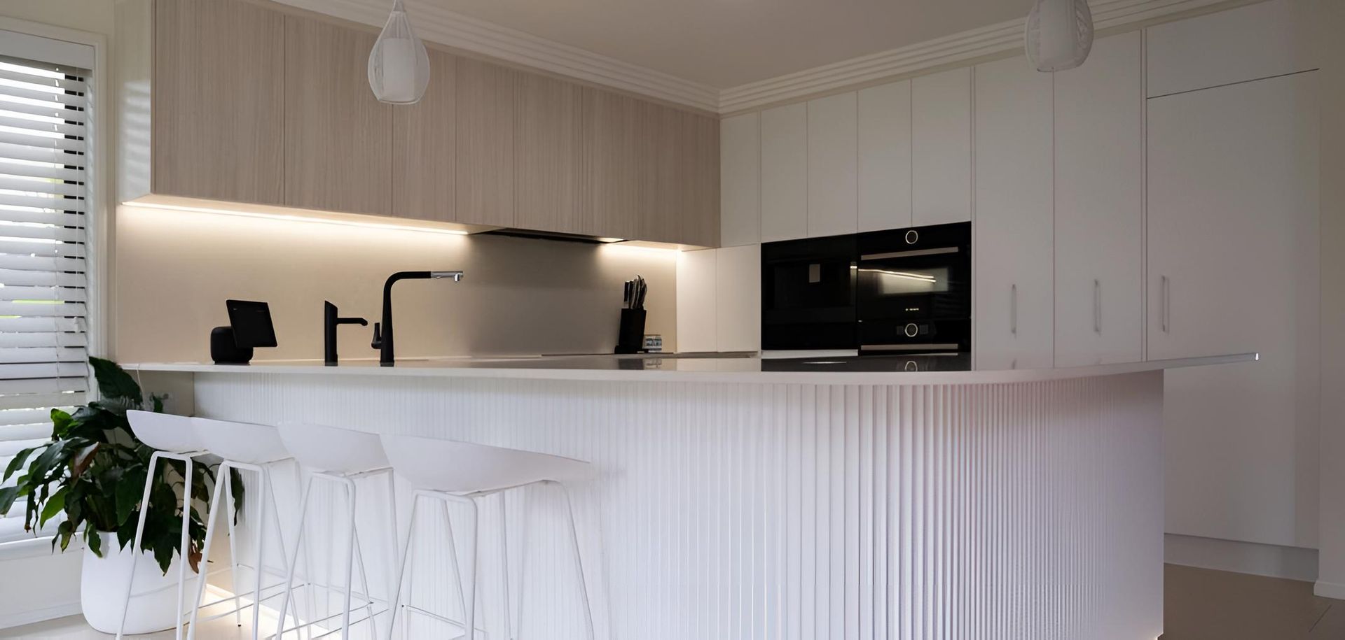 A Kitchen With White Cabinets and Stools and a Large Island — CK Cabinetry in Coolum Beach, QLD