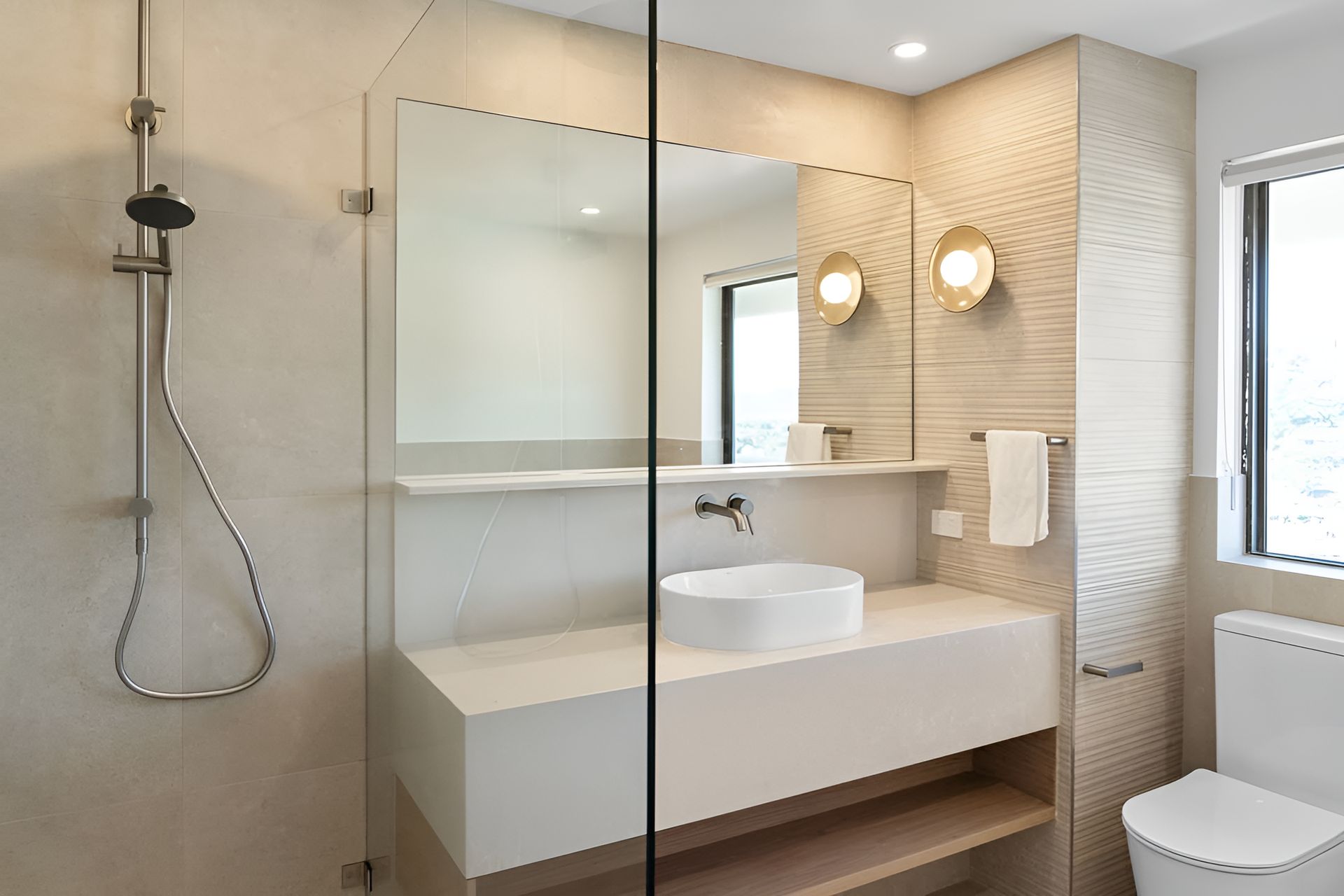 Modern bathroom with shower, floating vanity, round sink, and toilet. Neutral tones and minimalist design