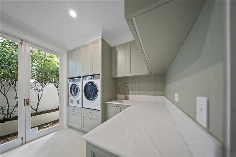 Laundry room with white counter, sage green cabinets, and double doors to a garden — CK Cabinetry in Coolum Beach, QLD