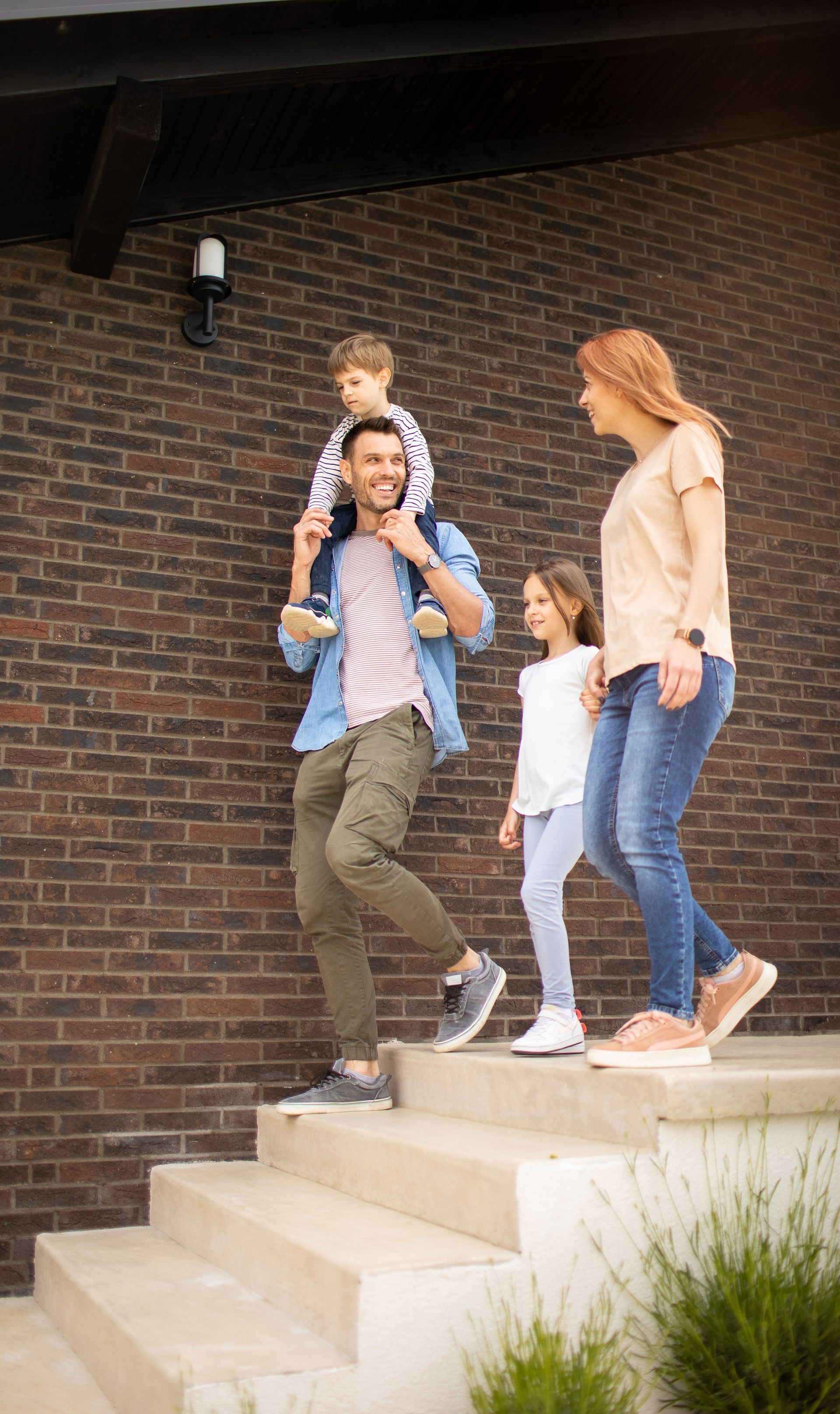 Family of four walking down outdoor stairs in front of a brick building.