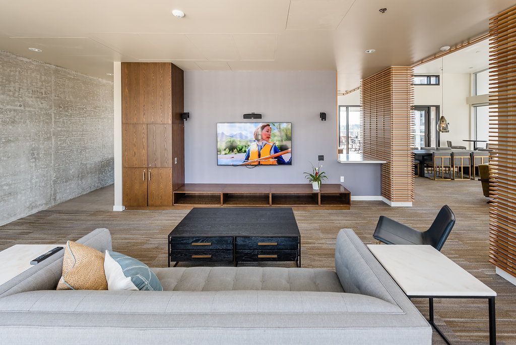 Apartment clubhouse with a couch and a flat screen tv on the wall.