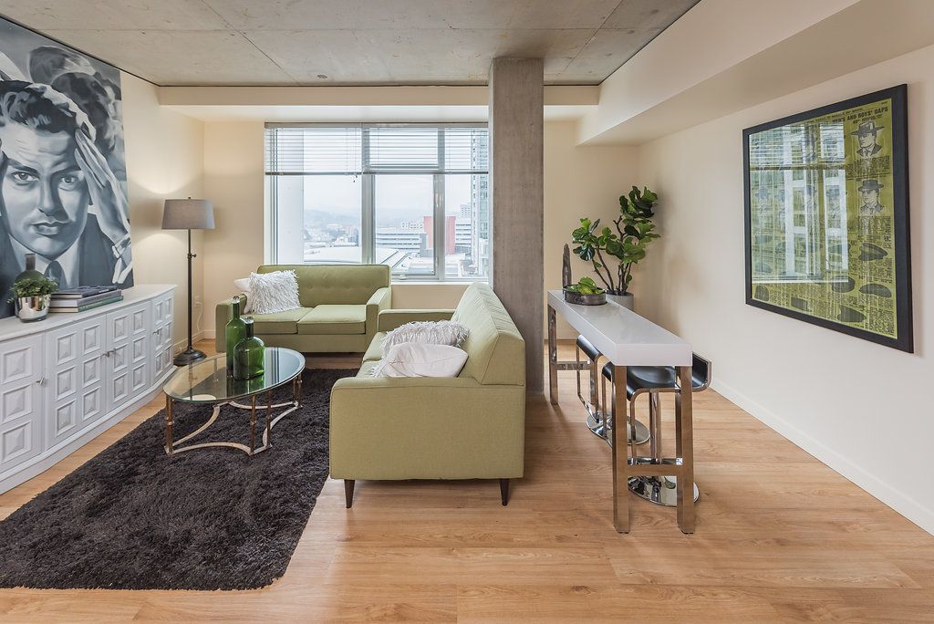 A living room with a green couch and a painting on the wall.