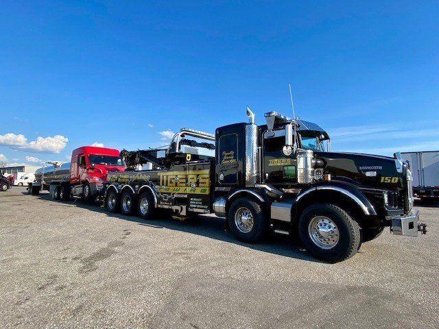 A Black Tow Truck Is Parked Next to A Red Truck in A Parking Lot — Battle Creek, MI — Tiger’s Towing