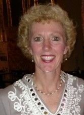 A woman wearing a necklace and earrings is smiling for the camera.