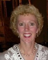 A woman wearing a necklace and earrings is smiling for the camera.