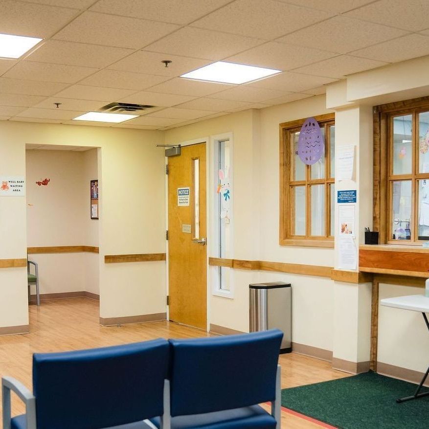 A waiting room with two blue chairs and a table
