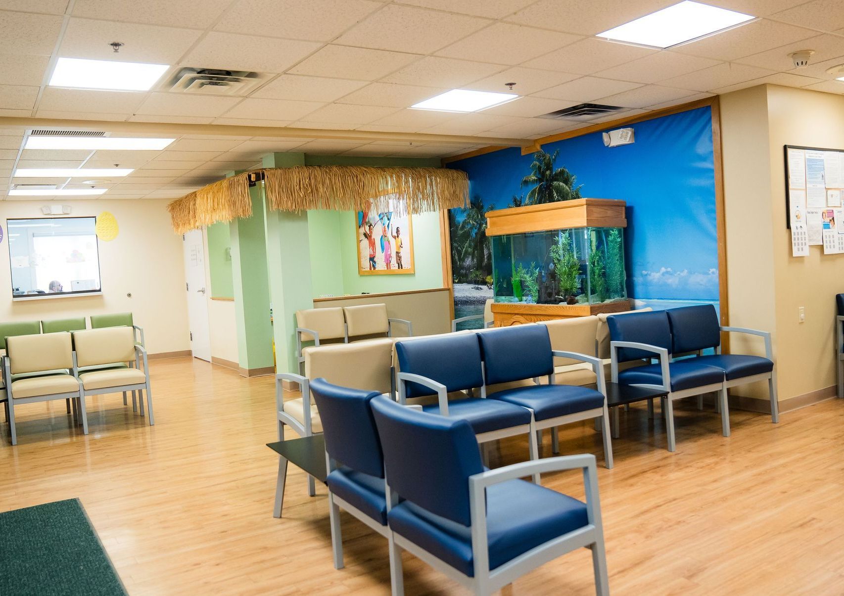 A waiting room with blue chairs and an aquarium on the wall.