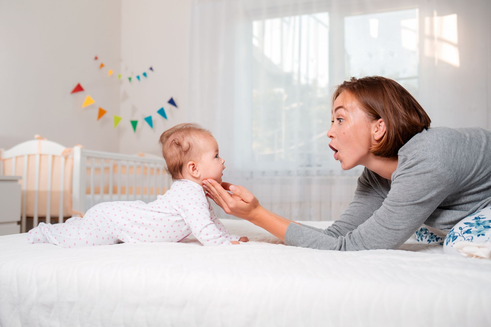 A woman is playing with a baby on a bed.