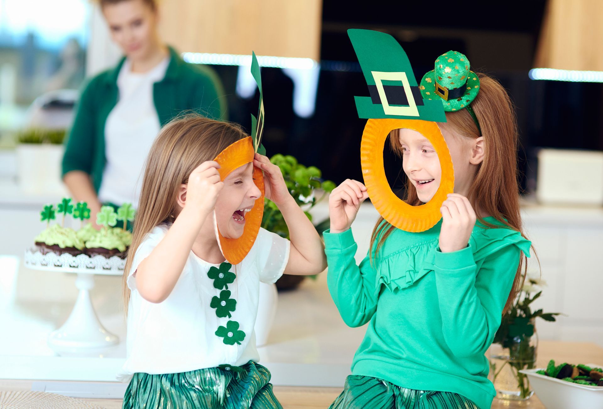 Two children in festive green outfits holding shamrock masks at a St. Patrick’s Day party