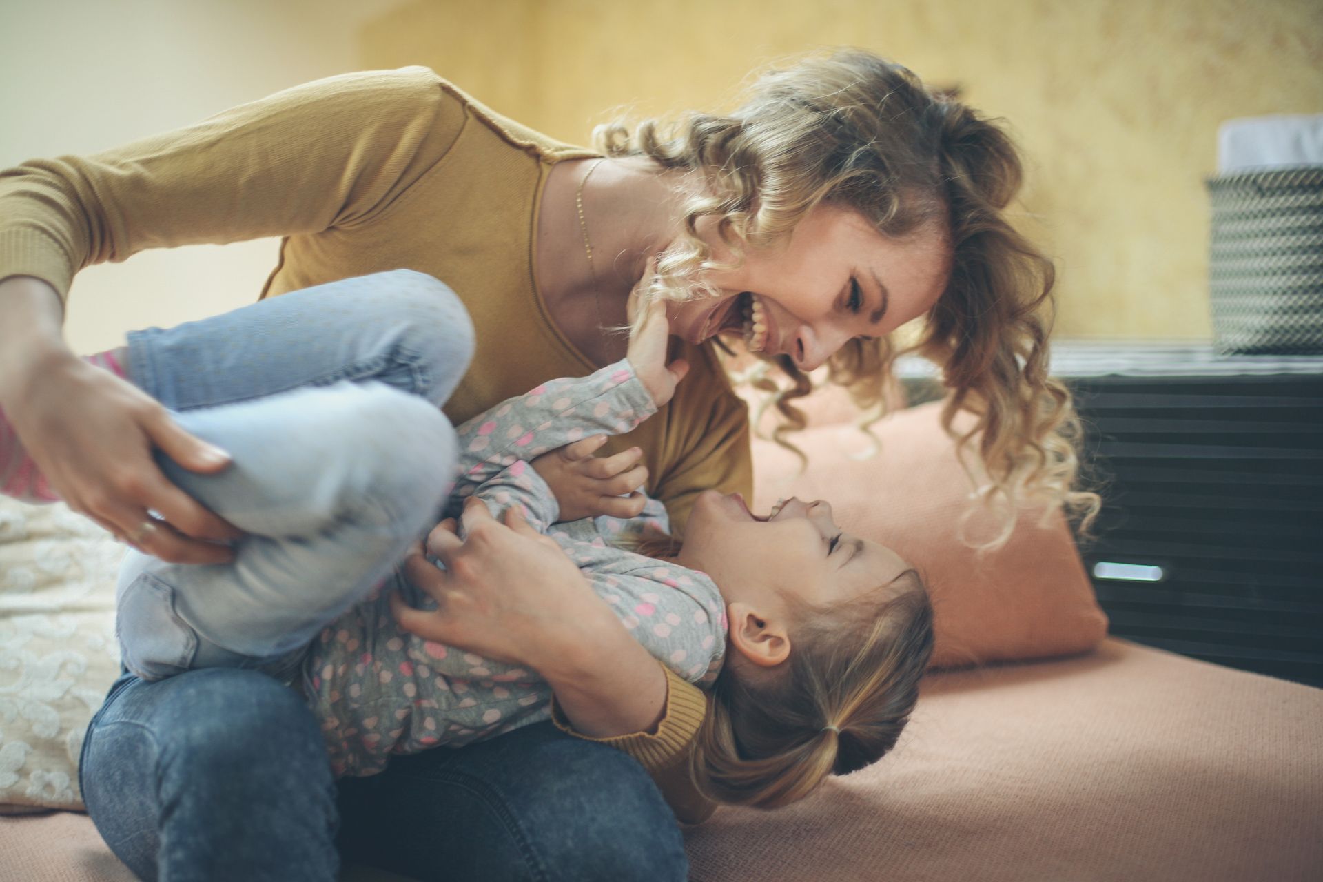 Mother hugging, laughing and smiling at her young daughter