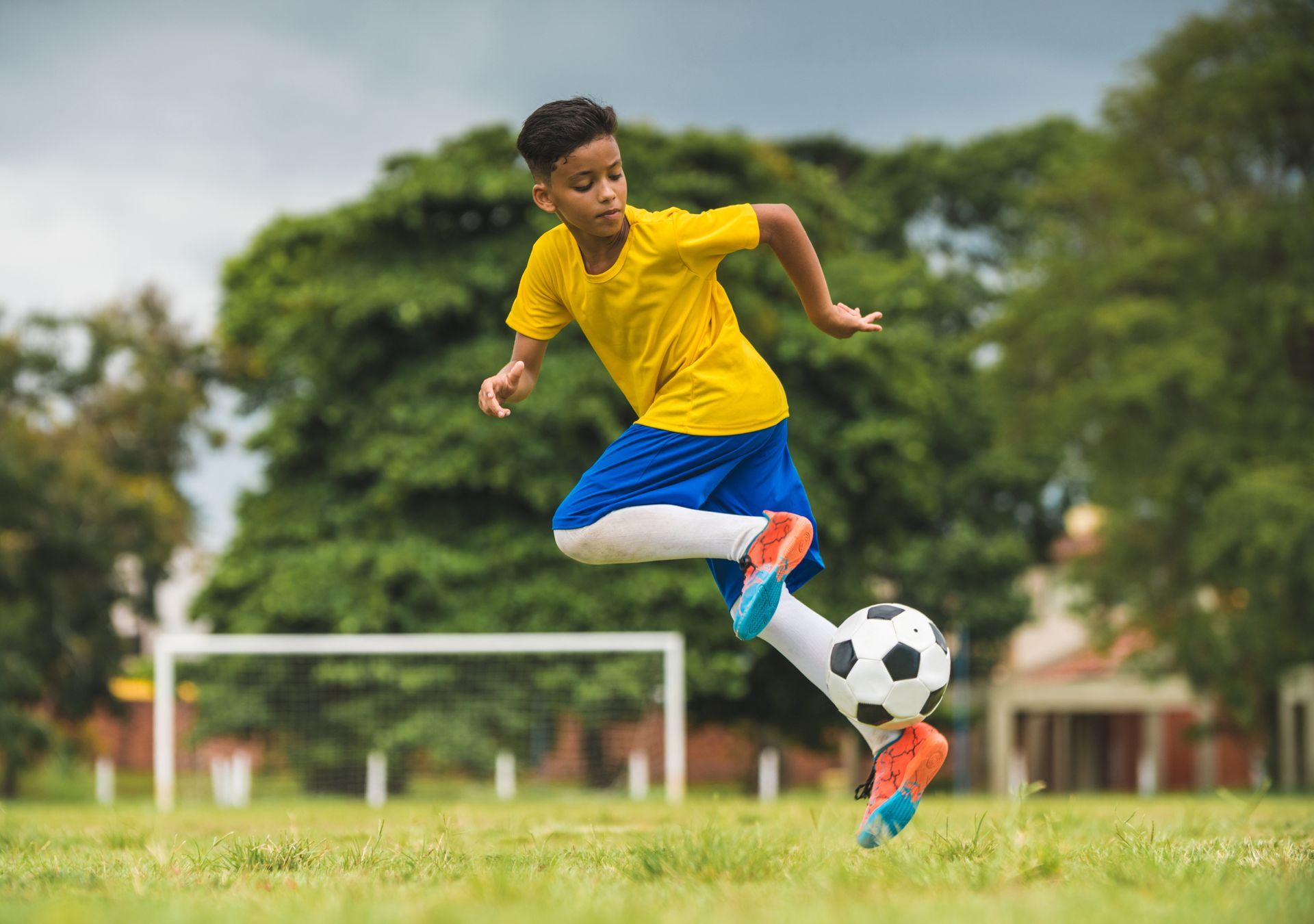 A young boy is kicking a soccer ball on a field.