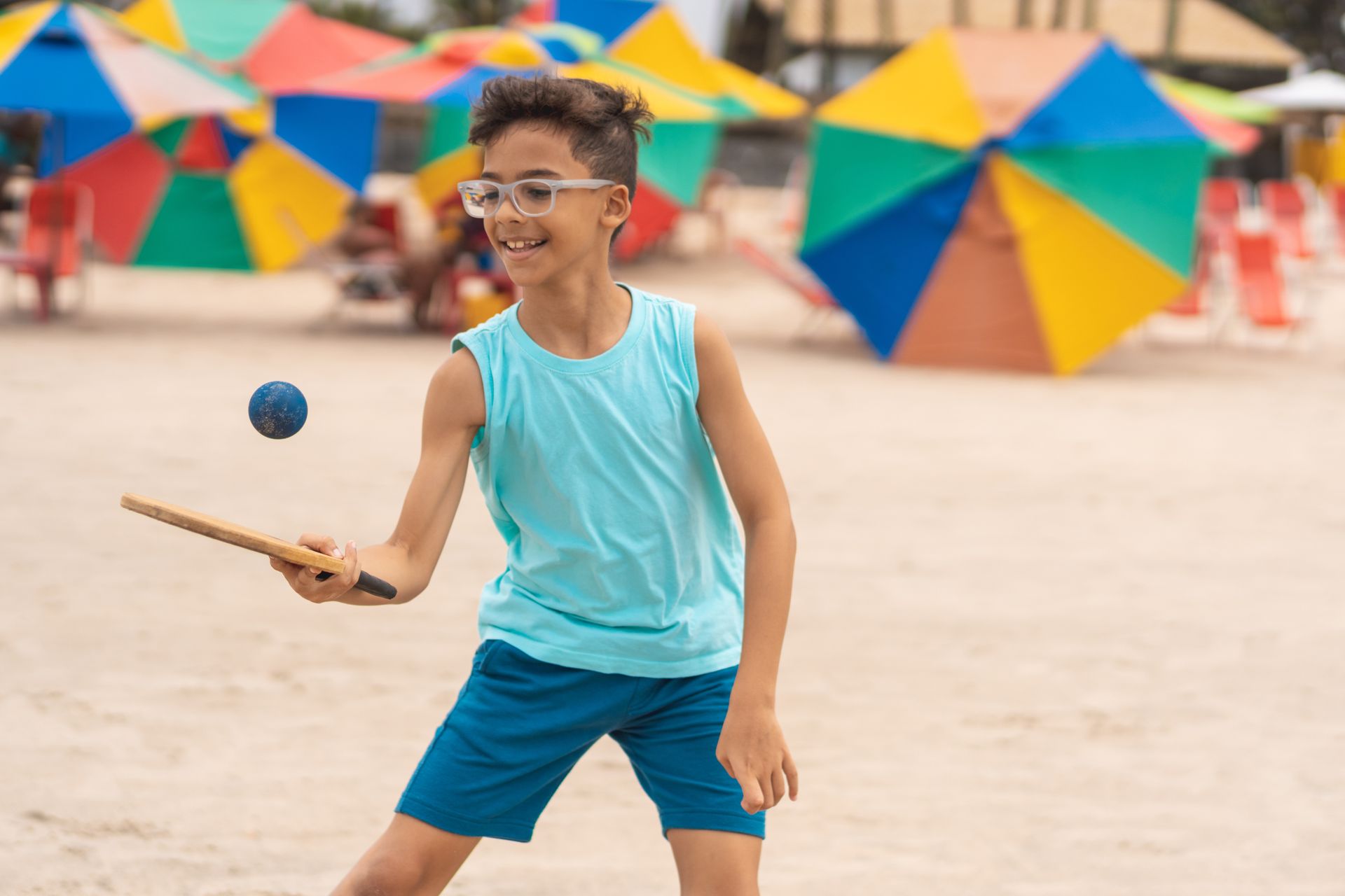 A young boy is playing with a ball on the beach.