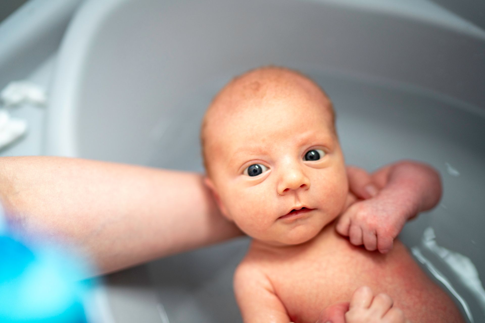 A newborn baby is taking a bath in a bathtub.