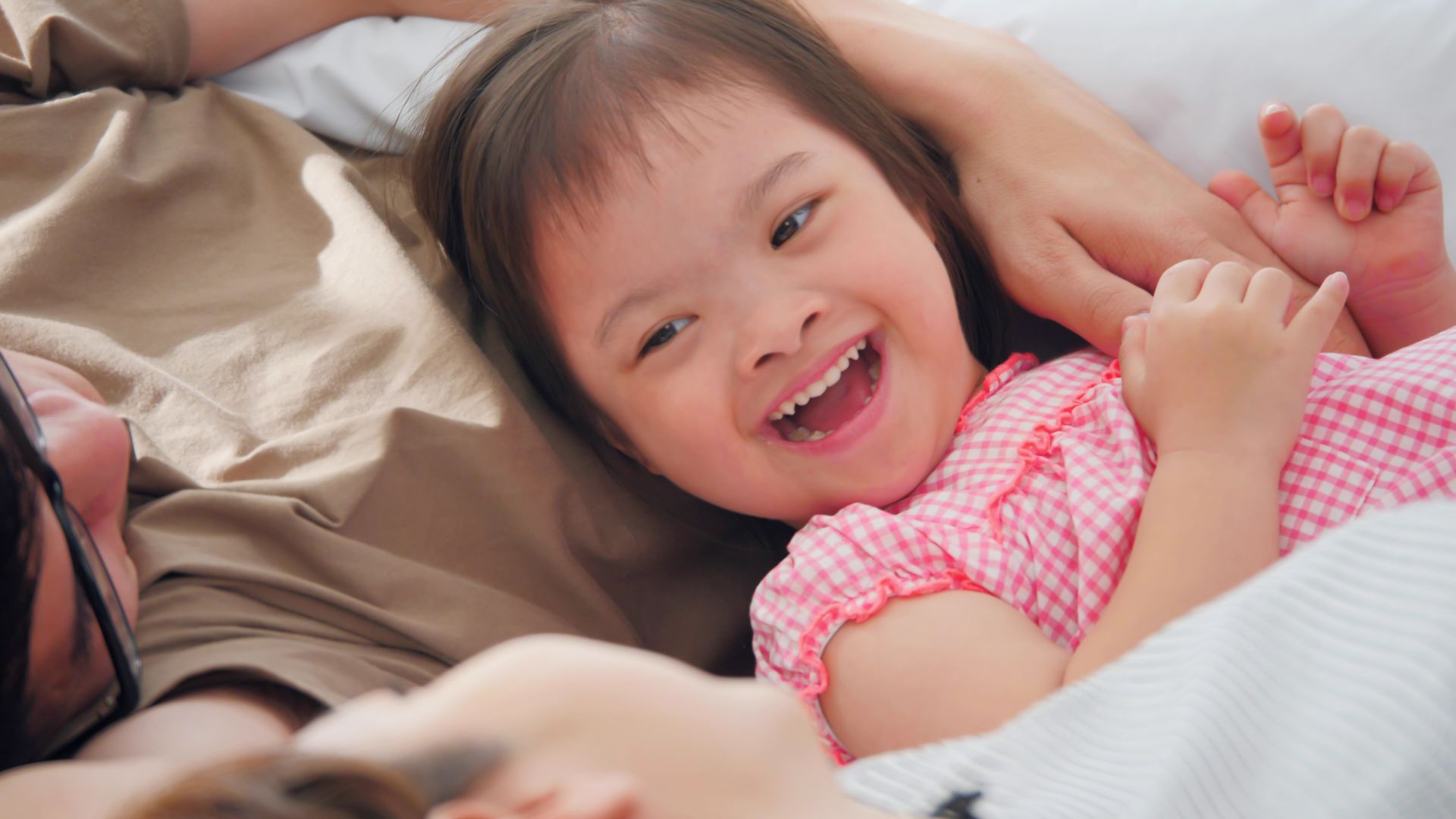 Smiling little girl leaning back on her parents' lap