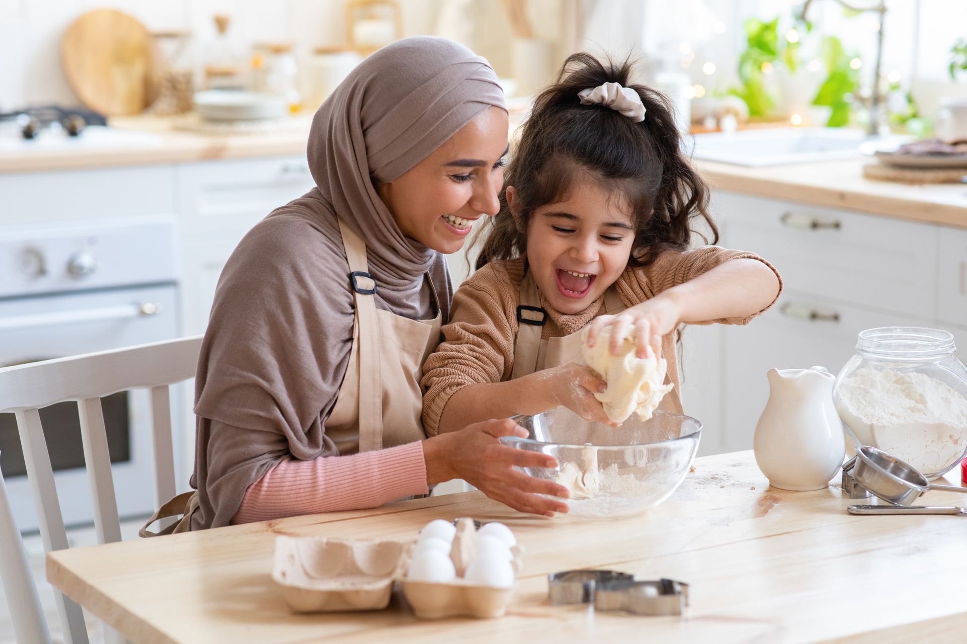 A woman and a little girl are preparing food in a kitchen.