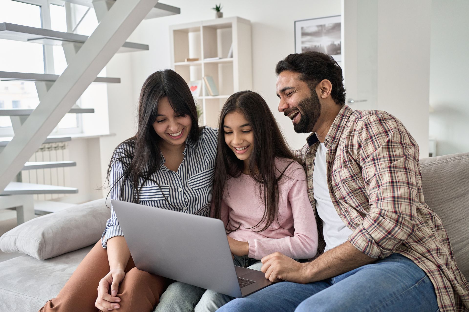 Two parent and adolescent daughter looking at a laptop together