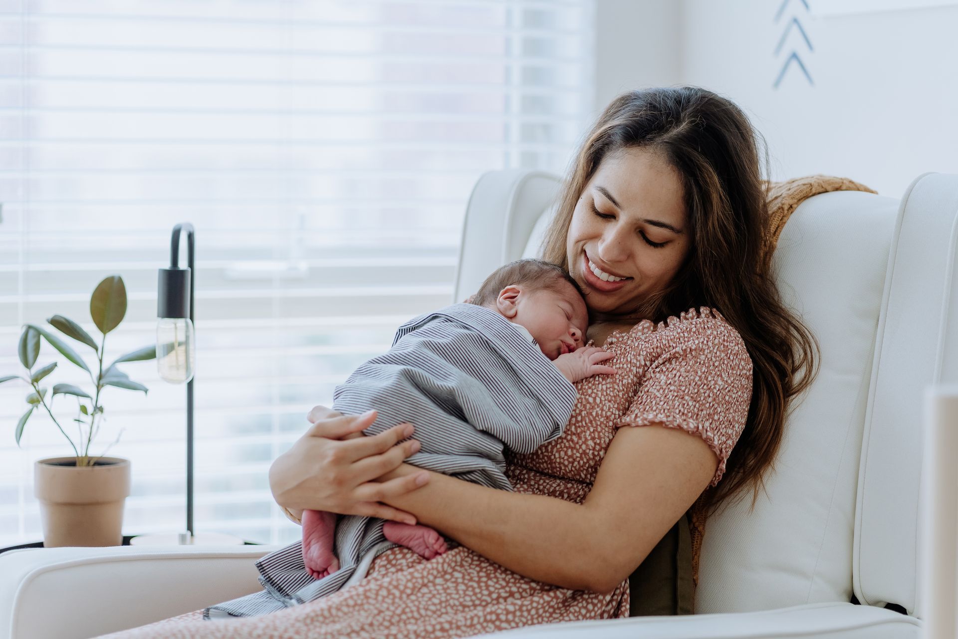 A woman is sitting in a chair holding a baby.