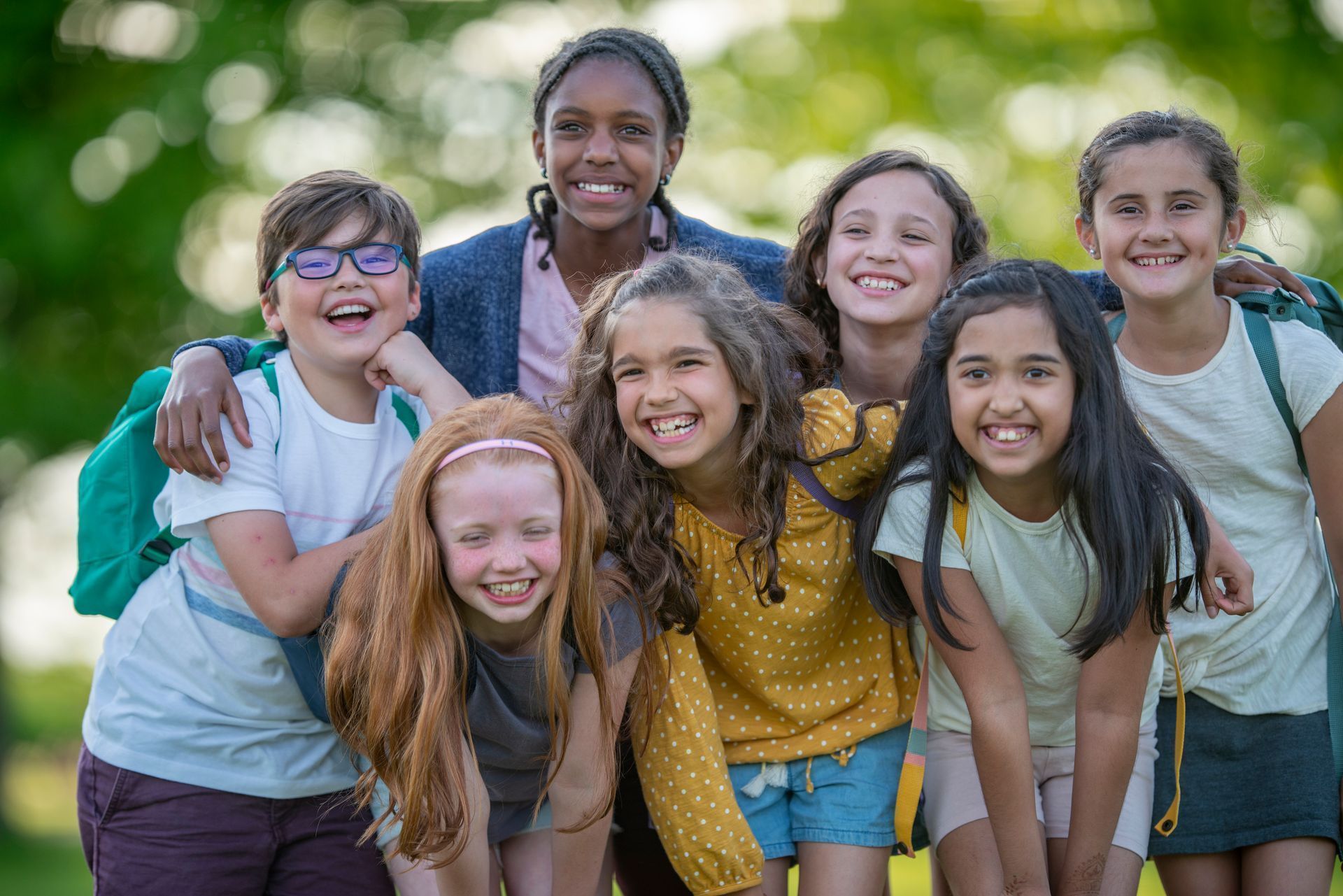 A group of children are posing for a picture together in a park.