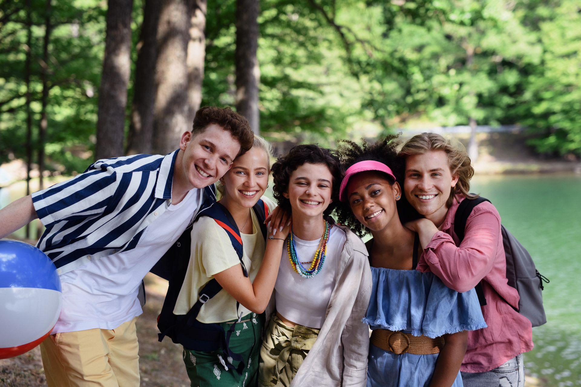 A group of young people are posing for a picture in front of a lake.