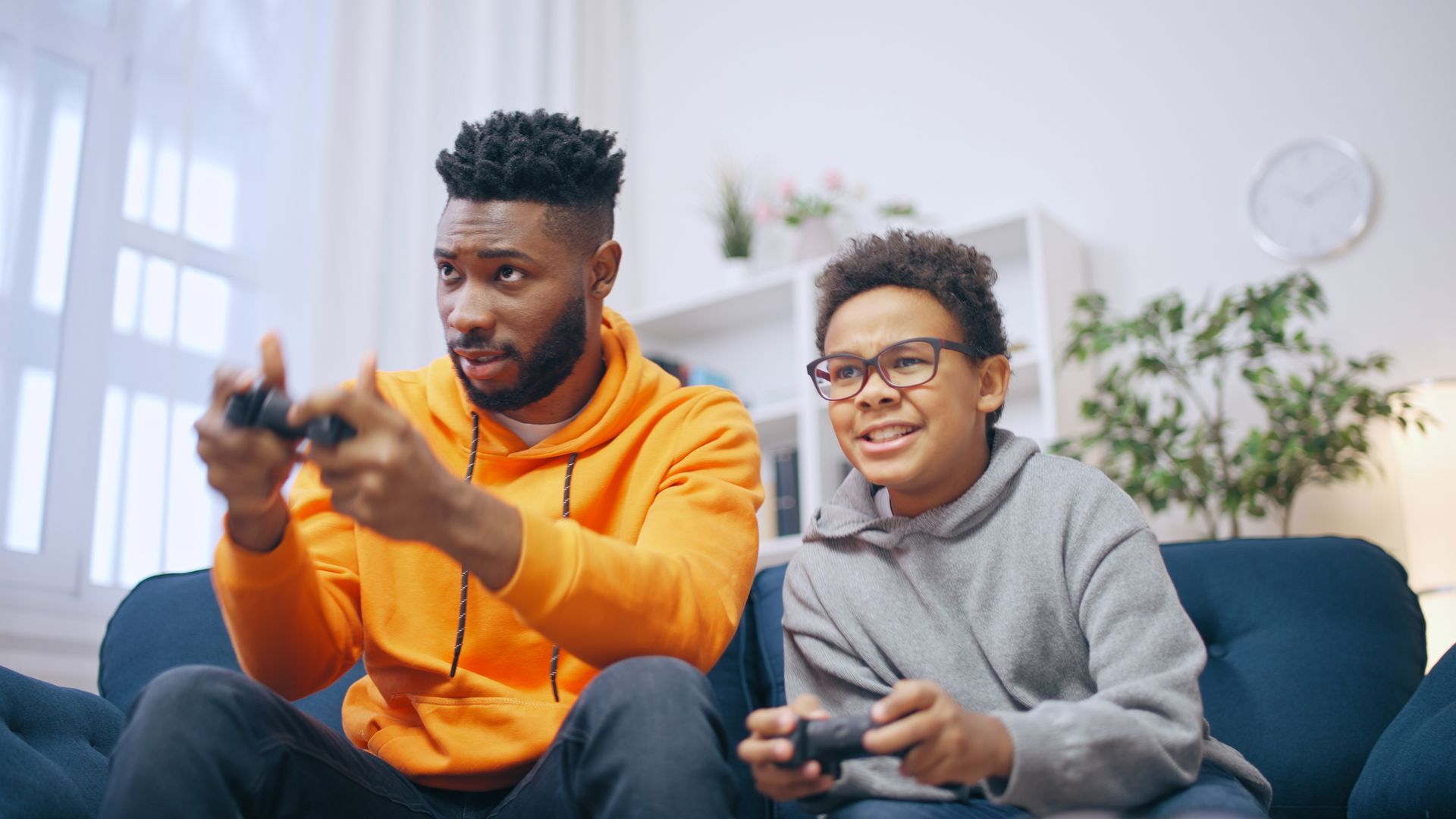 A man and a boy are sitting on a couch playing a video game.