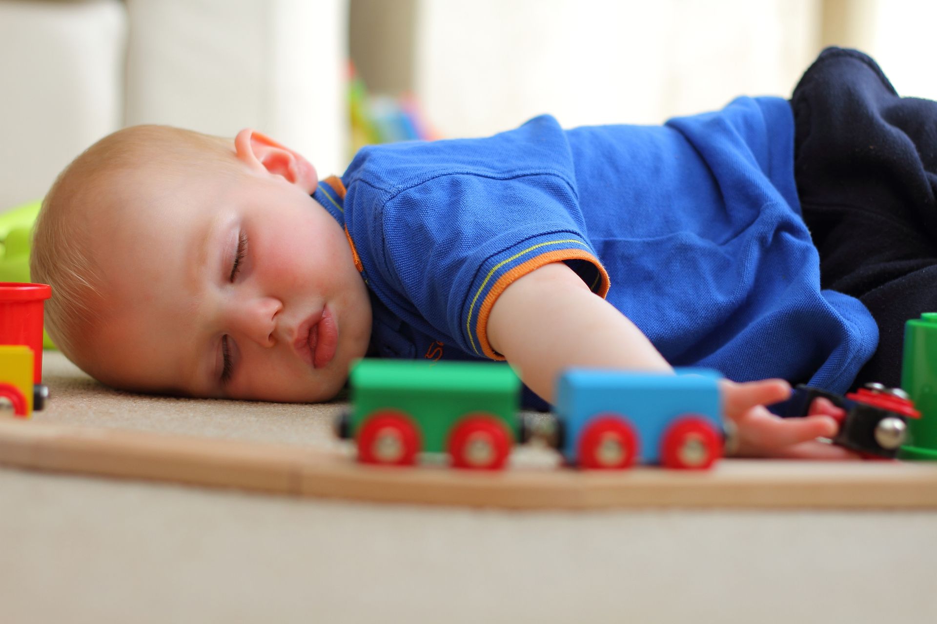 A baby is laying on the floor playing with a toy train