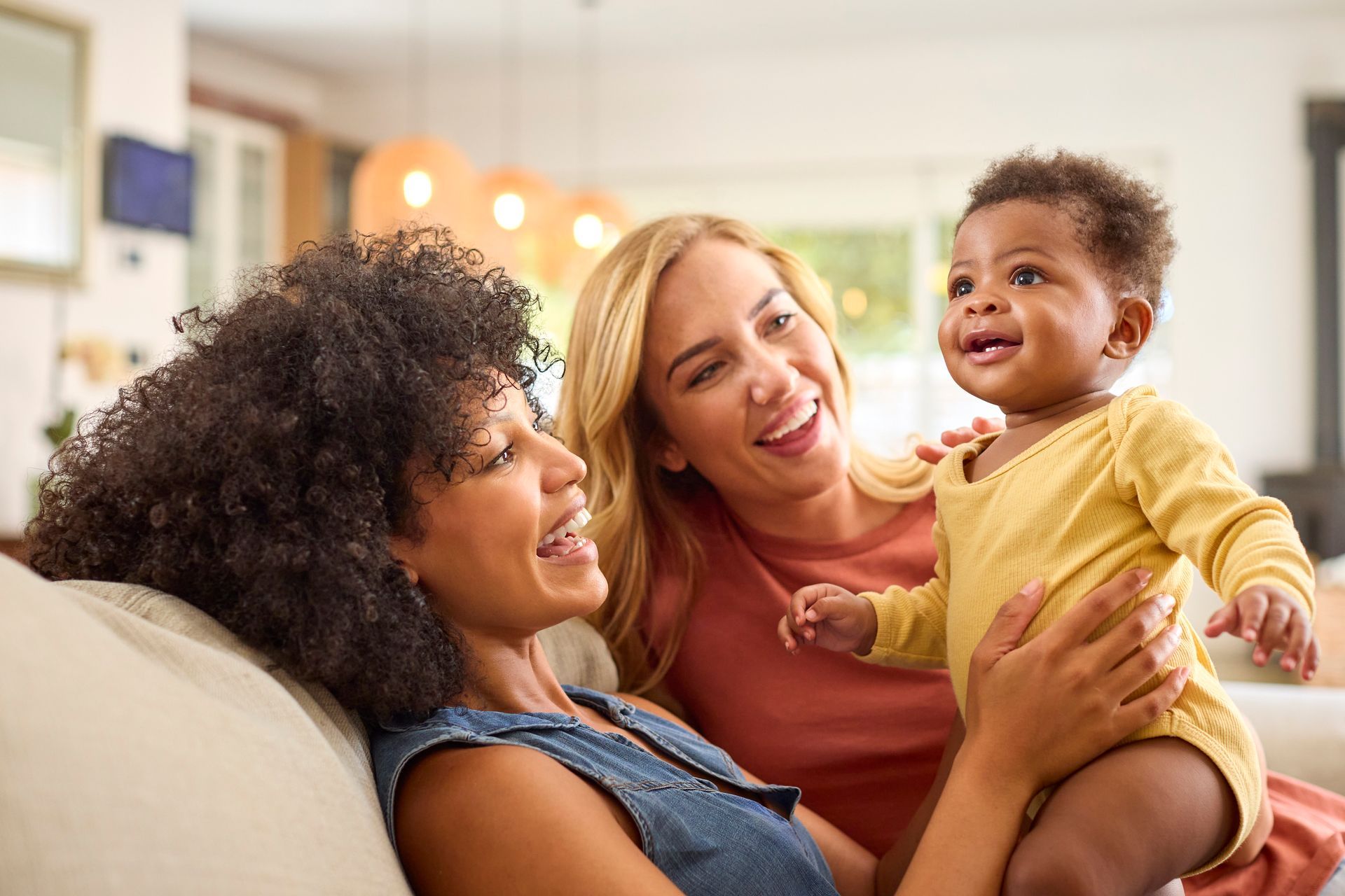 Two women smiling while holding a baby