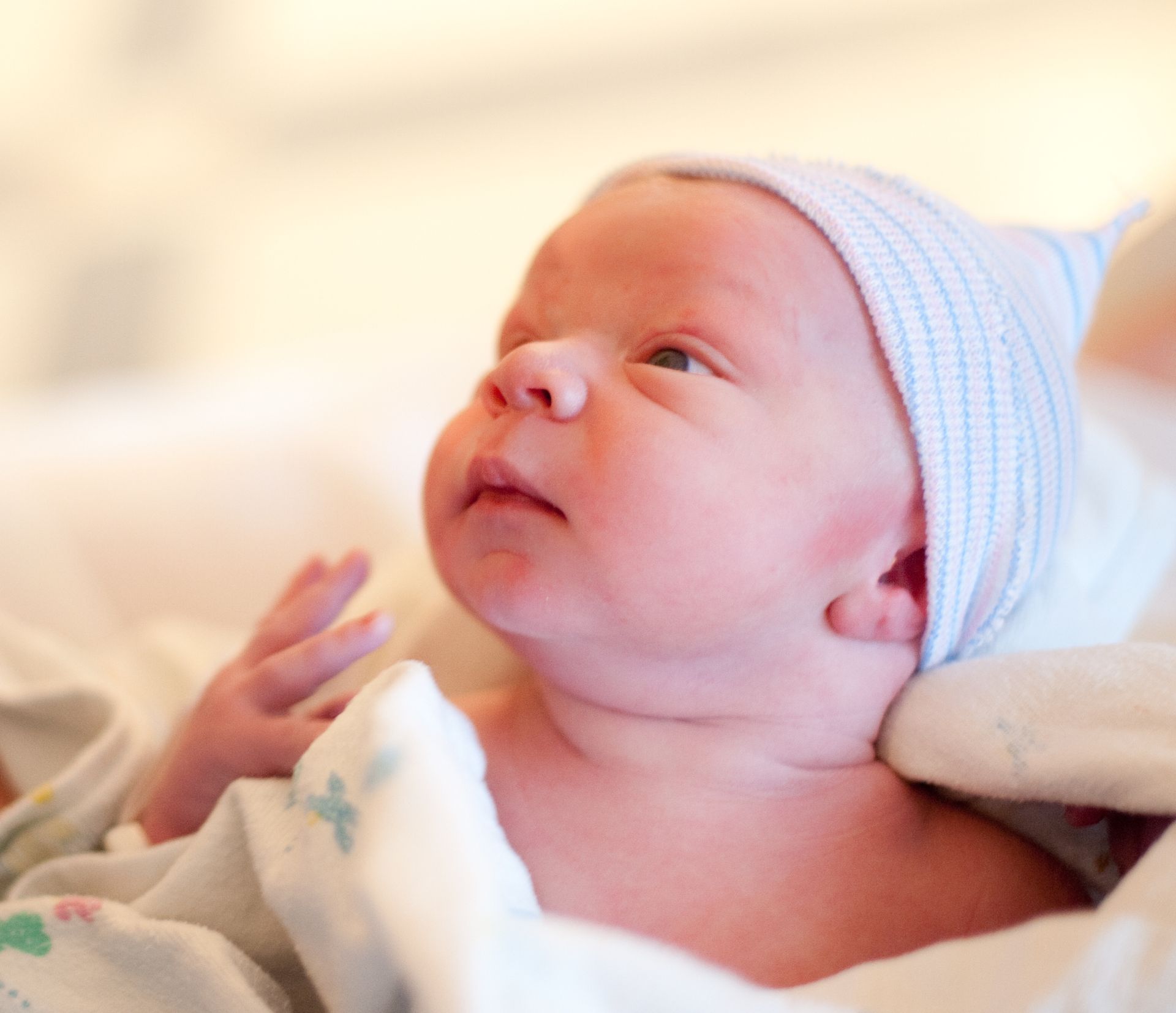 A baby is wearing a white hat and looking up