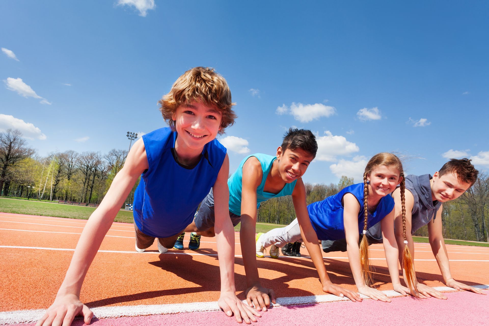 A group of children are doing push ups on a track.