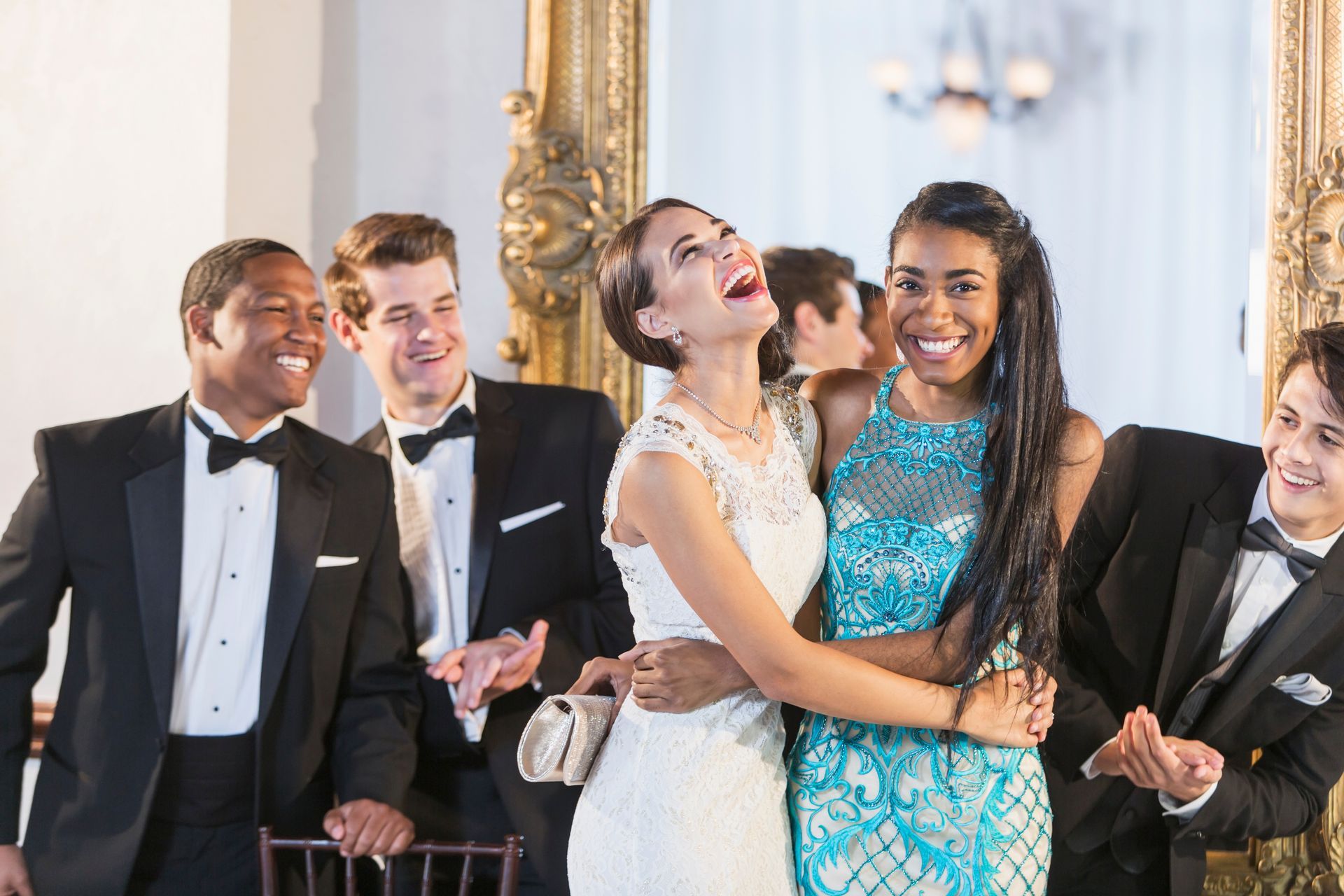 A group of people are standing around a bride and groom laughing.