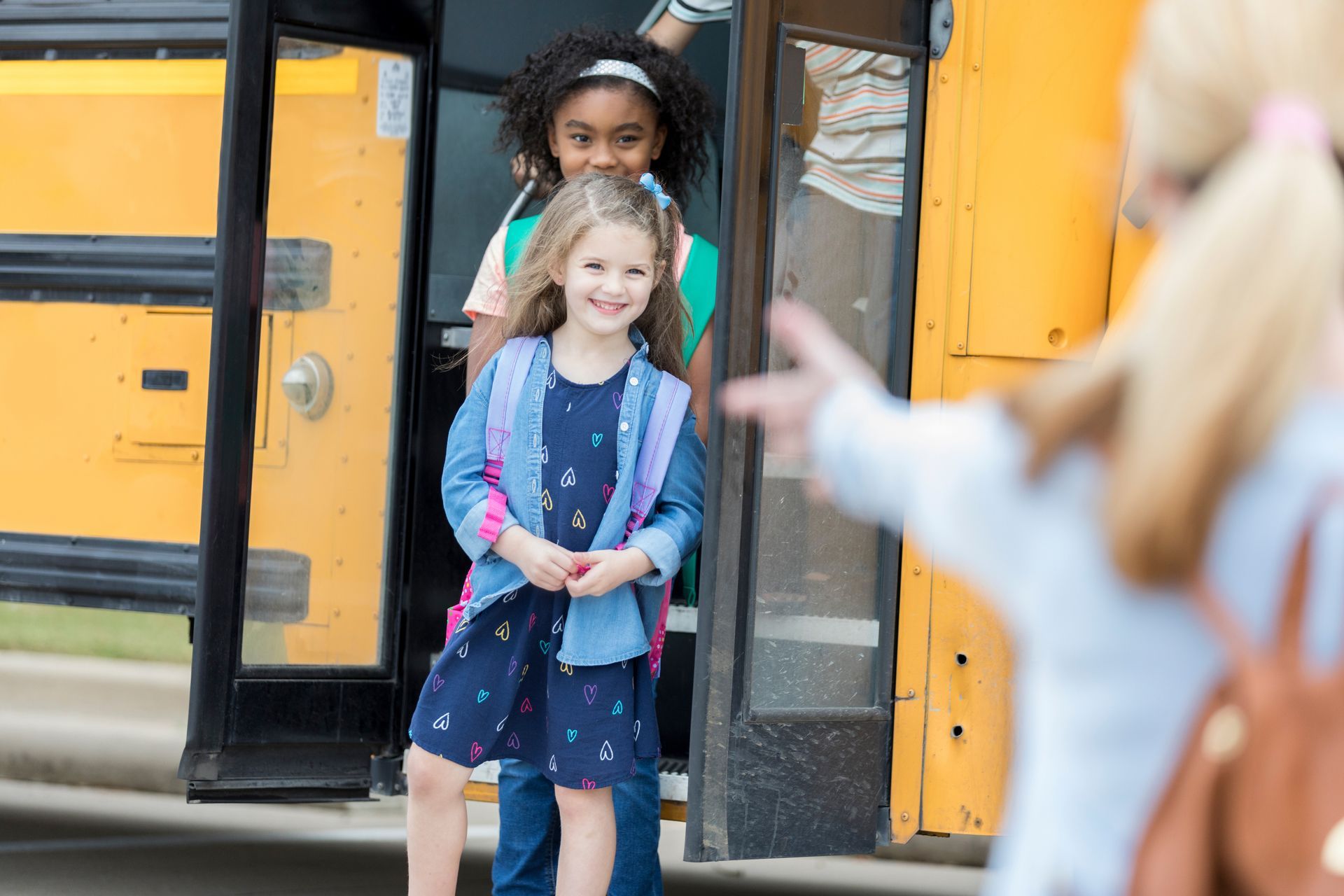 A group of young girls are getting off a school bus.