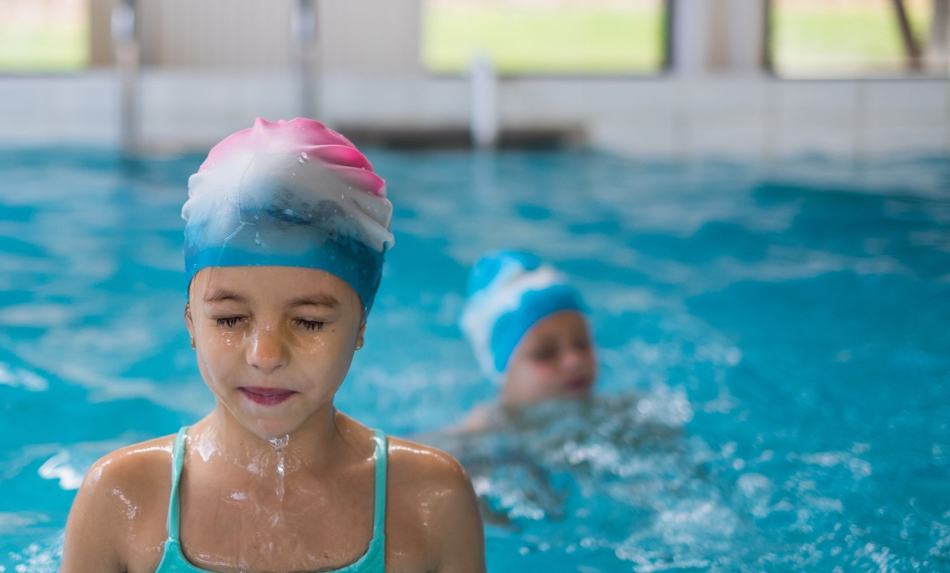 Two young girls are swimming in a swimming pool.