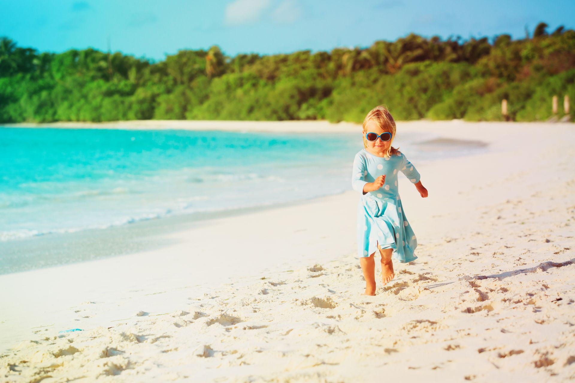 A little girl is running on the beach.