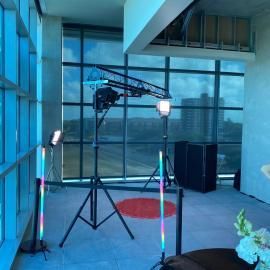 Modern glass studio with camera crane, lights, and tripods on a concrete floor