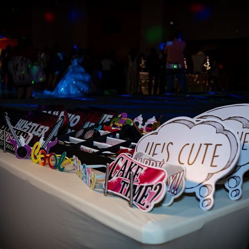 Decorated dessert table with colorful cake toppers and a “Who’s cute?” sign at a party