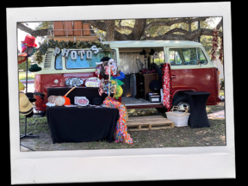 Vintage red-and-teal van with Halloween decorations and a table display at an outdoor market