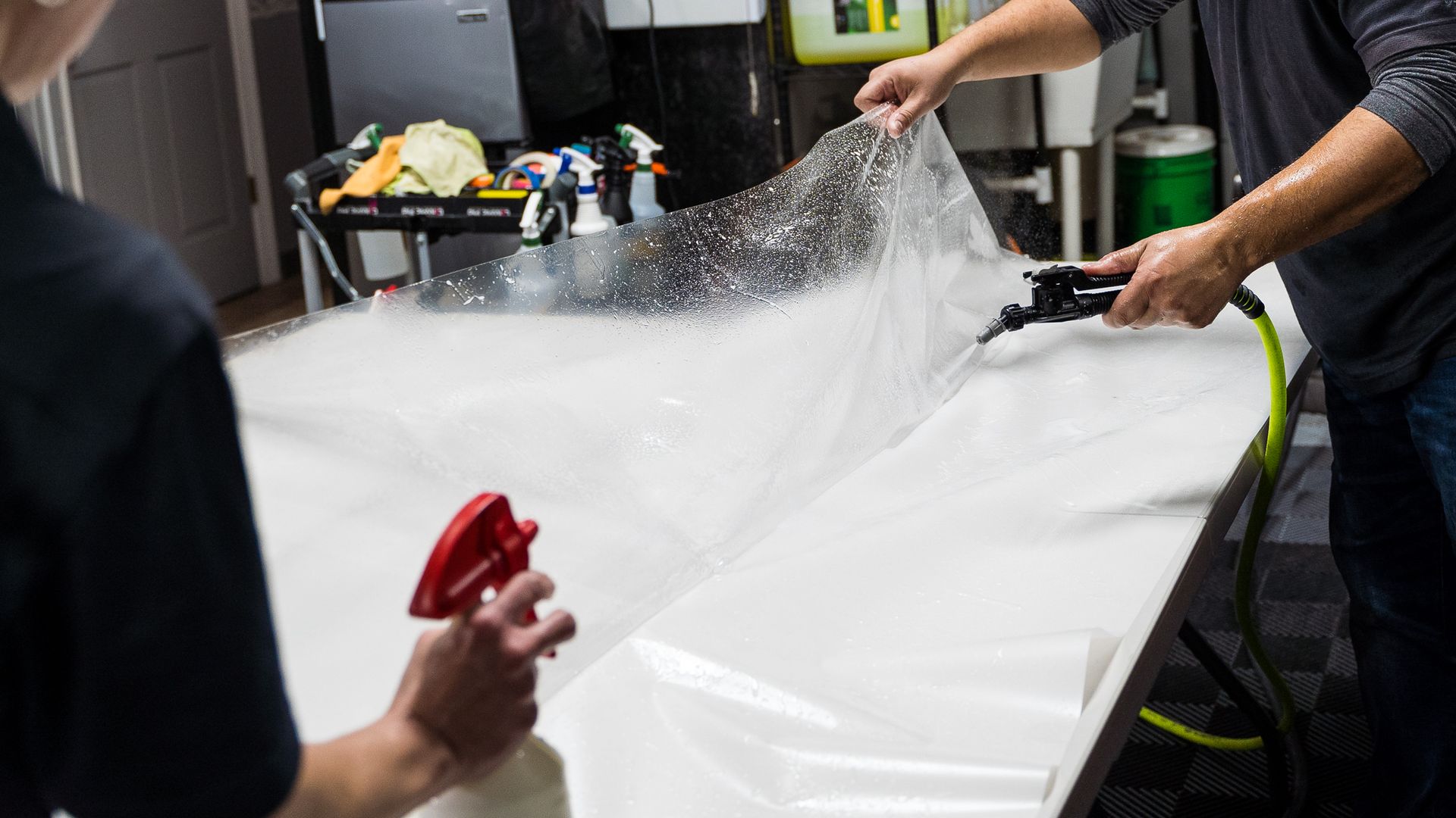 A man is spraying foam on a white surface with a spray bottle.
