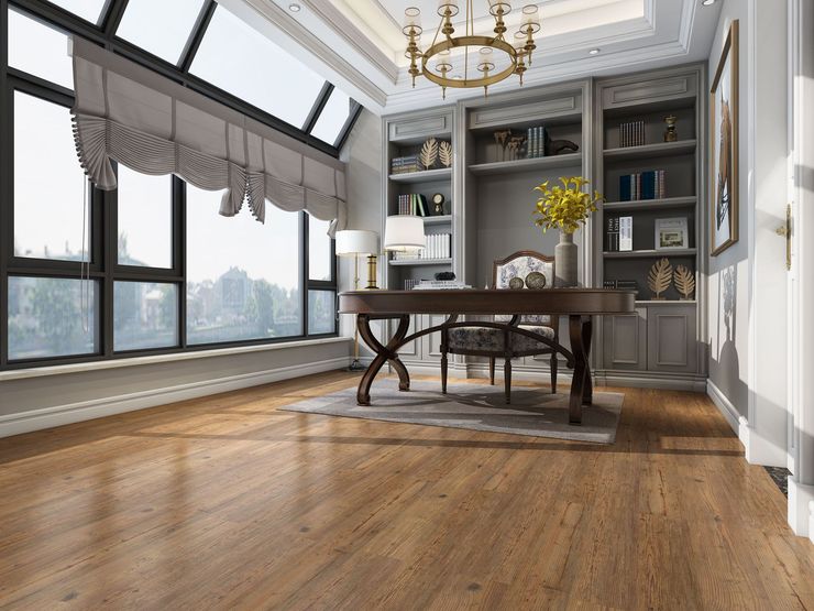 A room with a wooden floor , a desk , chairs , shelves and a chandelier.