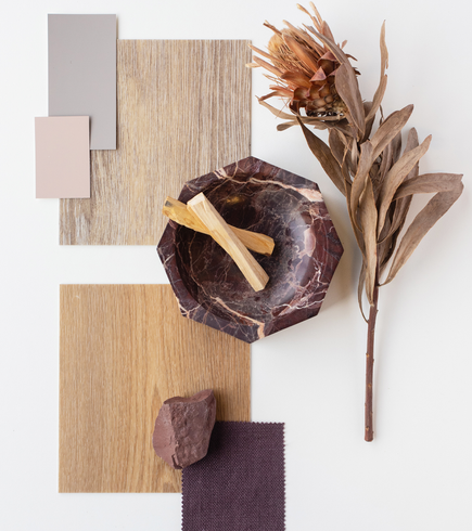 A wooden bowl with sticks in it is surrounded by wooden boards and flowers.