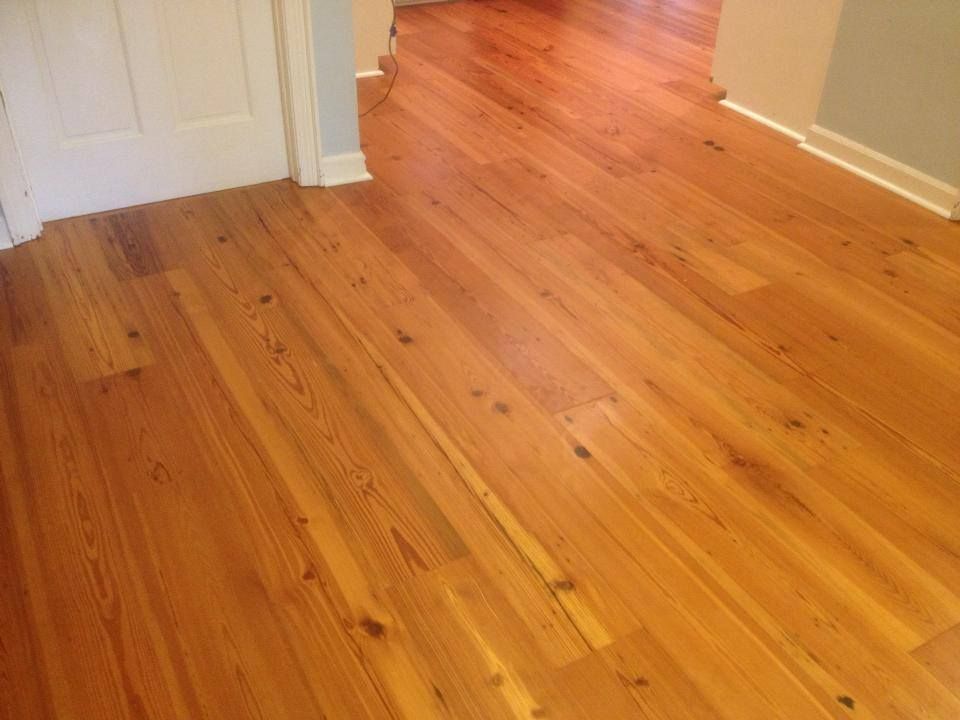 A wooden floor in a hallway next to a door.