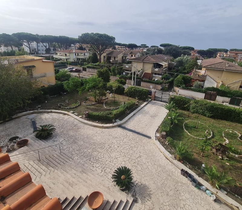 Cortile terrazzato e giardino con sentieri in pietra, tetti di tegole rosse e case in un quartiere residenziale