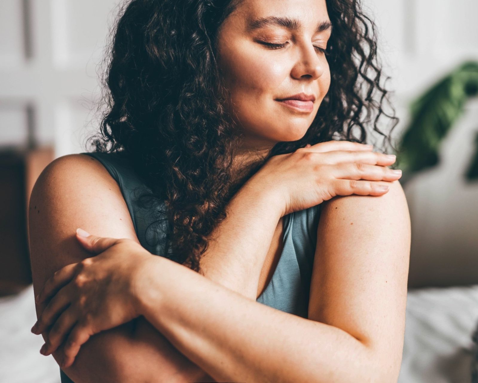 Woman gently hugging herself, symbolizing self-trust and boundary work supported through online therapy in California and Oakland.
